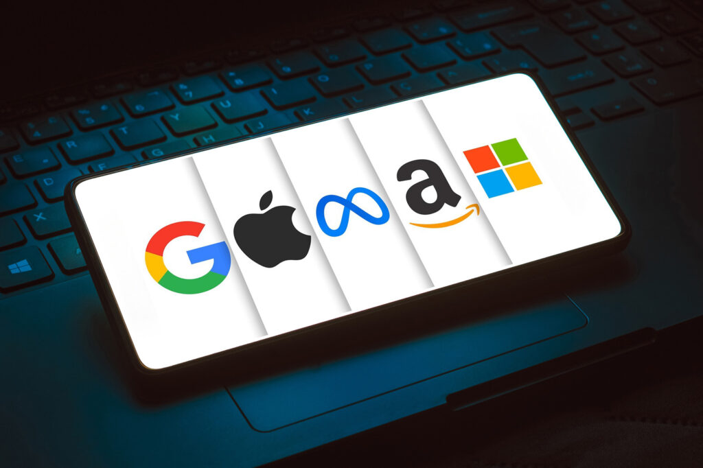 A smartphone showcasing logos of Google, Apple, Meta, Amazon, and Microsoft rests on a laptop keyboard. The backdrop subtly hints at the transformative power of technologies like Google Cloud AI.